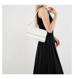 Detail of white crossbody bag featuring geometric triangle quilting and knotted strap