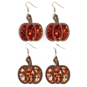 Close-up of wooden pumpkin earrings with sparkling dark red and orange glitter inlay