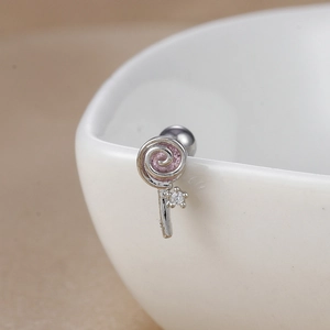 Macro shot of silver lollipop stud earring with pink swirl and zircon on a ceramic bowl
