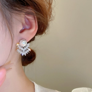 Close-up of elegant pearl stud earrings with marquise-cut crystals on a female model