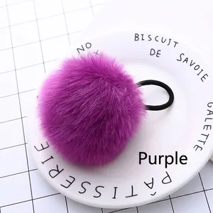 Detailed close-up of a fluffy purple faux fur pom pom hair tie on a white ceramic plate