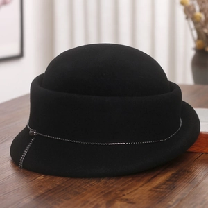 Close-up of black wool cloche hat featuring silver metal chain and tassel decoration