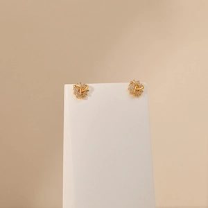 Detailed macro view of gold plated spiral flower earrings with white zircon stones
