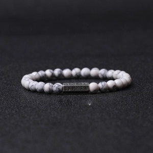 Vue macro de perles en pierre marbrée de 6mm et breloque mantra argentée sur bracelet