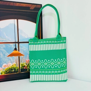 Detail of green knit tote bag featuring white geometric stripes and diamond patterns