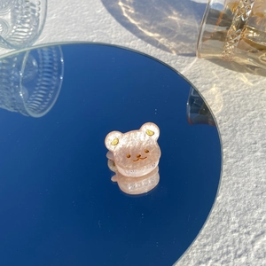 Détail d'une pince à cheveux ours rose pailletée avec reflet sur un miroir bleu élégant