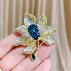 Detail einer Luxus-Blumenbrosche mit großem blauen Tropfenkristall und weißen Zirkonblüten