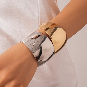 Macro detail of glossy gold and silver liquid metal bangles on a silk background