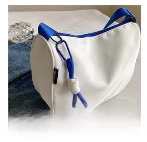 Detail of white nylon shoulder bag with blue textile strap and fashion knot accessory