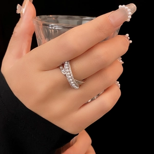 Detail of silver-tone hollow cross ring with white pearls on model holding a glass
