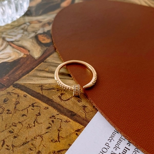 Detailed view of a gold-plated circular open ring with sparkling crystal inlay on leather