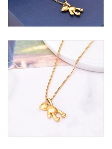 Macro detail of 18K gold plated teddy bear pendant with polished finish on blue background