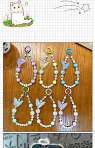 Collection of six colorful noctilucent butterfly beaded phone charms on wooden surface