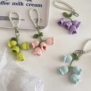 Close-up of handmade crochet lily of the valley keychains with pearl straps