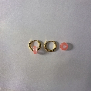 Detail of 18k gold plated hoop earrings with pink natural stone texture pendants
