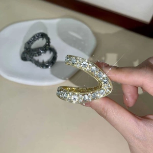 Dettaglio molletta per capelli dorata con strass scintillanti e variante nera sullo sfondo sfocato