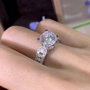 Macro view of classic four-prong round zircon engagement ring with pave diamond band