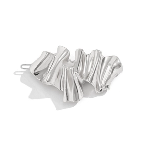 Detailed view of silver liquid metal hair clip with irregular geometric fold texture