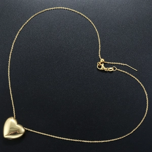 Detailed view of a golden heart pendant necklace arranged in a heart shape on a black base