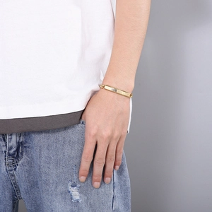 Close-up of a men's gold stainless steel Roman numeral plate bracelet on a male wrist
