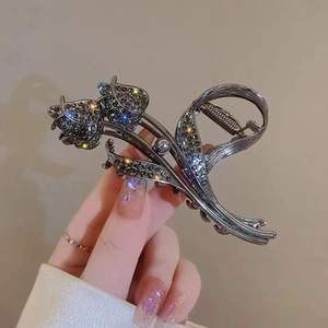 Detailed macro view of dark tulip hair claw clip with rhinestones and grey pearl accent