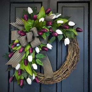 Artificial purple and white tulip wreath with ribbon on dark wood door for home decor