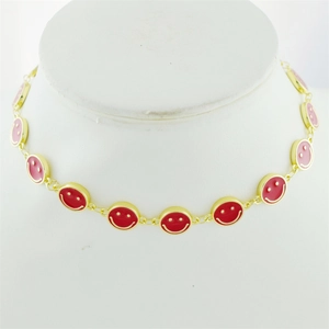 Detailed view of golden necklace chain featuring multiple red enamel smiley face pendants