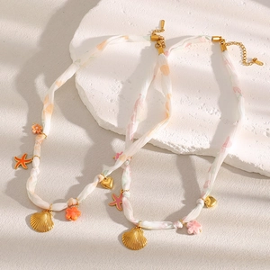Detail of 18K gold-plated ribbon necklace with shell, starfish, and heart charms