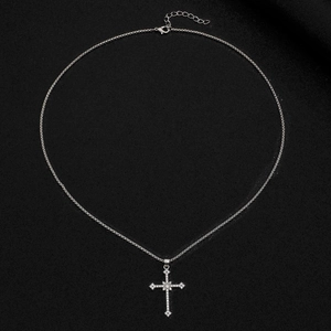 Détail du collier croix gothique argentée avec cristaux sur un fond noir profond