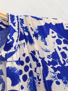Detail of blue and white floral print neckline and pleated shoulder stitching on fabric