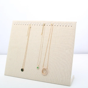 Close-up of beige microfiber necklace display stand with metal hooks and linen texture