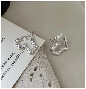 Dettaglio di orecchini a cuore in argento con trama in metallo liquido su pietra