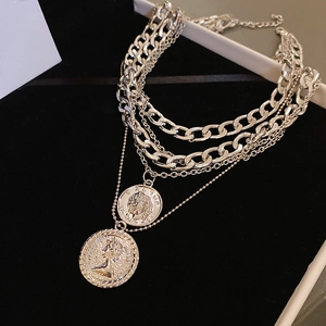Detail of silver layered chain necklace featuring vintage coin pendants on black display