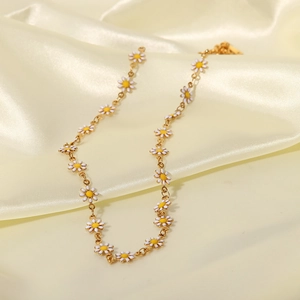 Primer plano detallado del collar de margaritas doradas sobre elegante tela de seda amarilla