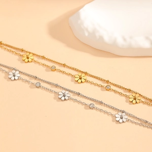 Gold and silver daisy chain bracelets with sparkling crystals on decorative stone