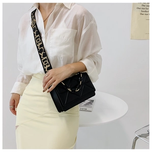 Detail of black crossbody bag with jacquard strap and acrylic chain decoration