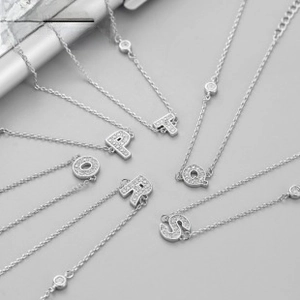 Gros plan des pendentifs lettres O à T en argent avec pavé de zircons sur chaînes