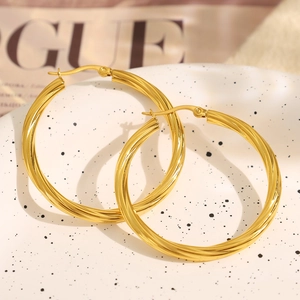 Polished golden twist-textured hoop earrings displayed on a luxury white jewelry tray