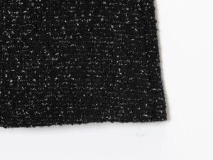 Gros plan sur un tissu en tweed bouclé noir avec une texture de boucles blanches