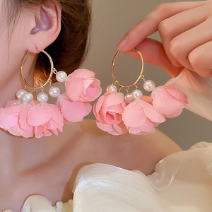 Detailed macro view of pink floral petal drop earrings with white pearls and gold hoops