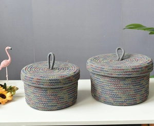 Detail of round woven storage baskets with lids in grey cotton rope and colorful accents