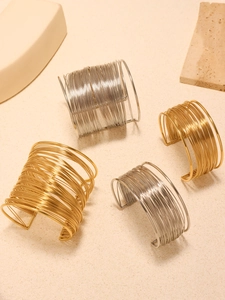 Macro detail of multi-layer gold and silver wire-wrapped wide open cuff bracelets