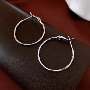 Polished silver textured hoop earrings with hammered finish on dark leather background