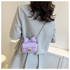 Close-up of lavender quilted mini crossbody bag with bow detail and gold chain strap