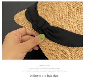 Detail of natural straw sun hat showing adjustable inner strap and black ribbon bow