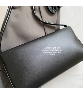 Close-up of minimalist black baguette shoulder bag featuring fine leather texture and strap