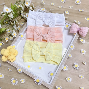 Detailed view of three soft nylon baby headbands with large bows on a rustic wooden tray