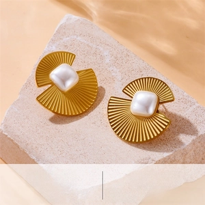 Macro shot of fan-shaped golden stainless steel earrings with square pearl on a stone