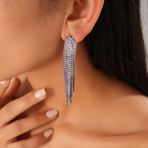Dettaglio di lunghi orecchini a frangia argentati con strass azzurri su una modella