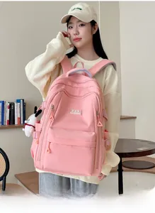 Pink student backpack detail showing multiple zippered compartments and plush charm